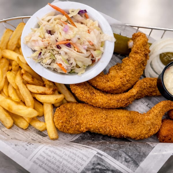 Fried fish and hush puppies with fries, coleslaw, and tartar sauce in a metal basket.